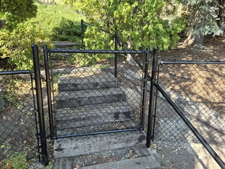 Black chain link gate opening onto timber steps